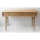 An oak side table with two spring-loaded half-width drawers, raised on slender high turned