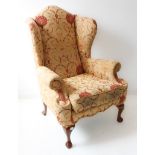 A good upholstered wingback armchair in early style (modern reproduction): stained-wood cabriole