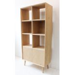 A modern oak shelf unit by Gallery Ltd: half-width square shelves and two cupboard doors below;
