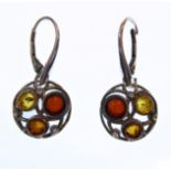 A pair of silver earrings: the circular droppers each set with three opposing stones of claret,