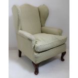 An early 20th century wing-backed armchair in early 18th century style; light lime-green