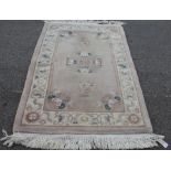 A small Chinese wool rug: the buff ground with a central floral medallion, floral vase pendants