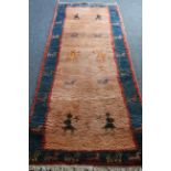 A thick and heavy hand-knotted woollen runner: salmon pink ground with stylised people and animals