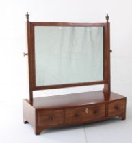An early 19th century bow-fronted mahogany toilet mirror: rectangular boxwood-strung plate flanked