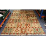 A flat-weave kilim rug with red, white and green repeating motifs against varying green horizontal