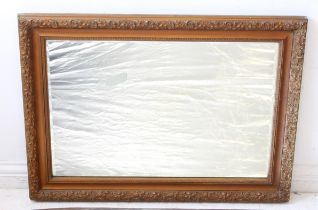 An Edwardian gilt and composition mirror: the rectangular bevelled plate within a foliate