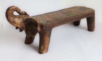 An African stool or seat carved from a single piece of softwood modelled as an elongated