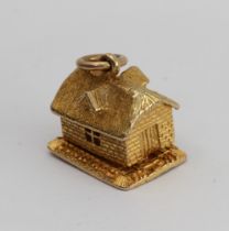 A 9-carat yellow gold charm modelled as a cottage opening on a hinge to reveal a bear asleep in