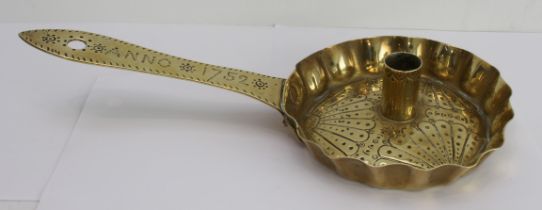 An 18th brass chamber stick decorated with fan shaped motifs, the handle dated 'Anno 1752'