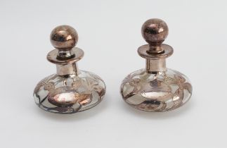 A pair of small early 20th century glass and silver overlay scent bottles: each decorated with