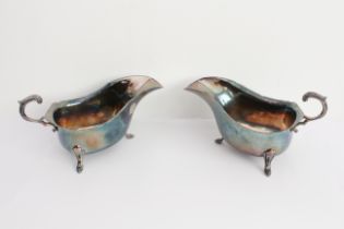 A pair of hallmarked silver sauceboats of generous proportions: high arched leaf-capped scrolling