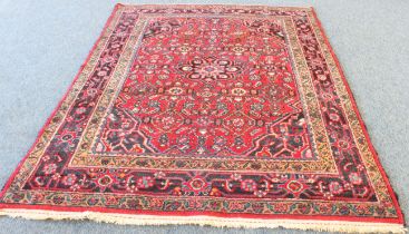 A Persian Hamadan rug; red ground with blue central medallion, floral sprays surrounded by four