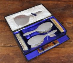 An early 20th century six-piece silver-mounted dressing table set comprising: two hairbrushes; two