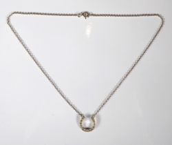 A horseshoe-shaped silver pendant set with small hand-cut white stones and upon a silver chain (