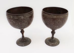 A pair of late 19th to early 20th century coconut cups (as goblets) incised with flowerheads,
