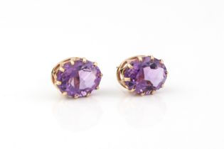 A pair of 9ct gold and amethyst stud earrings - the 10 x 7.75mm oval cut amethysts in basket