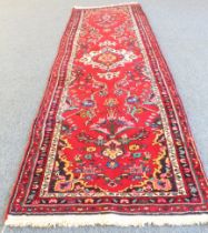 A Persian Hamadan runner; red ground with ivory central medallion and sprays of flowers surrounded