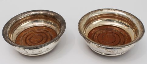 A pair of modern hallmarked silver wine bottle coasters with turned wooden bases: maker's mark PHV &