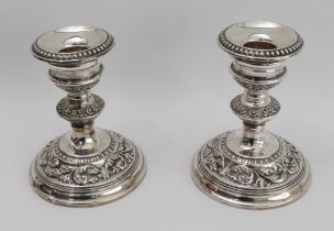 A pair of modern, hallmarked silver, weighted candlesticks: spreading circular feet decorated with