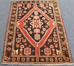 A Persian Hamadan rug with large dark brown central medallion surrounded by three borders, late 20th