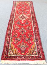 A Persian Hamadan runner; red ground with ivory central medallion surrounded by flowers (294 x 89