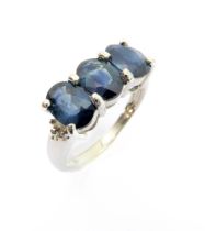 A 9-carat white gold dress ring: horizontally set with three hand-cut oval sapphires within claw