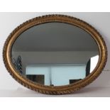 An oval gilt and composition mirror - the late 19th century frame with gadrooned border and shot