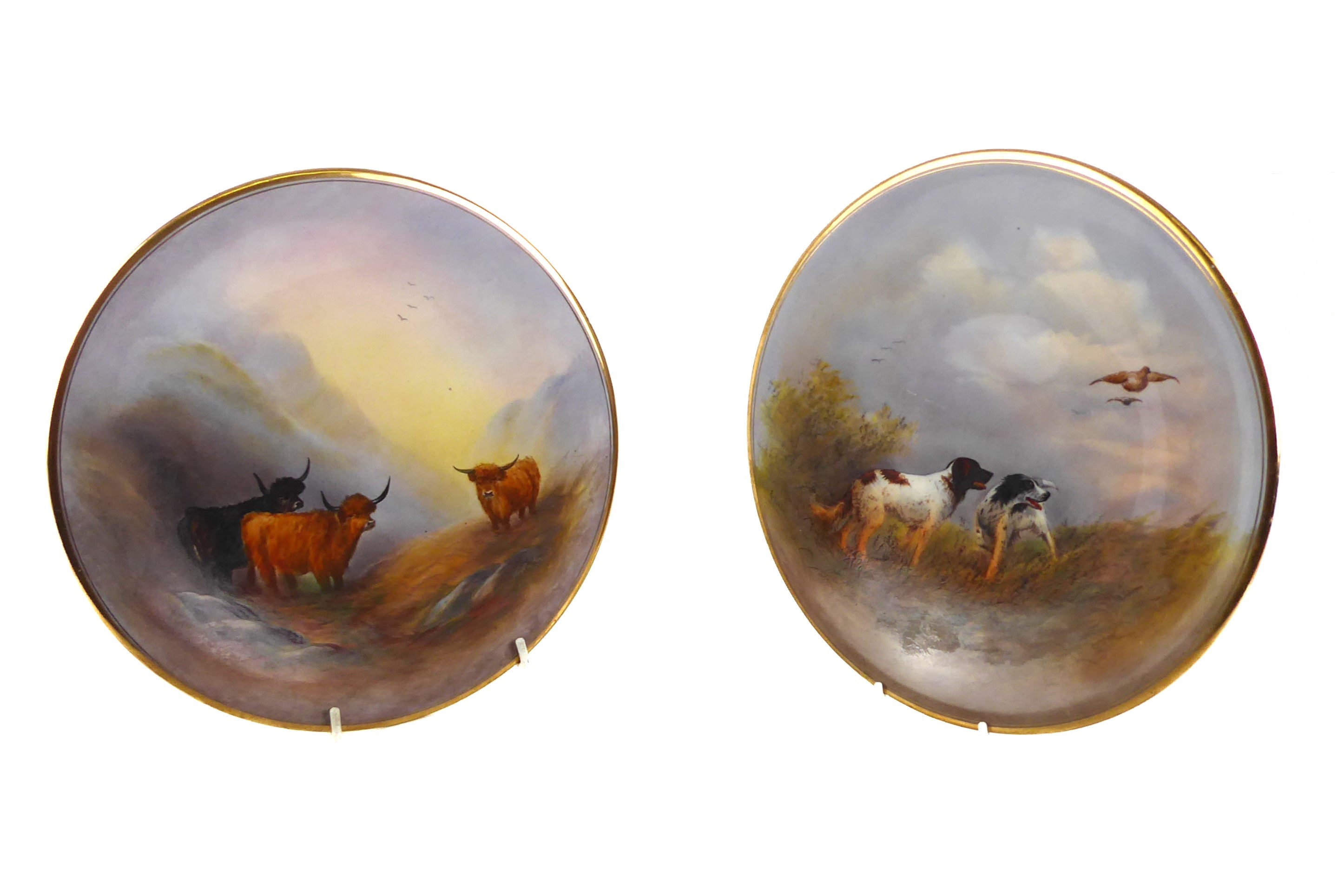 A pair of early 20th century Crown Devon ceramic hand painted wall-hanging plates: one decorated