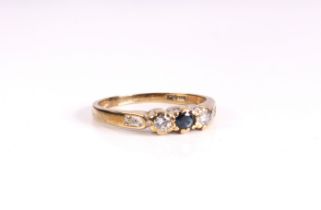 A 9ct yellow gold, sapphire and diamond ring - the central round cut sapphire flanked by two