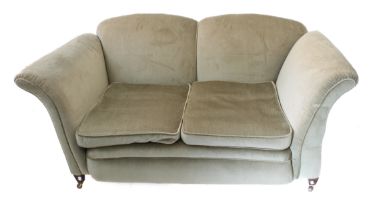 An early 20th century green upholstered two-seater drop-end sofa raised on short square tapering