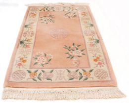 A small Chinese woollen rug - late 20th century, with flowers and vases on a pink ground, within a