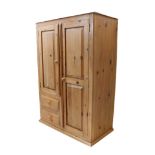 A pine cupboard with two panelled doors - the right revealing a hanging rail and shelf below, the