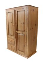 A pine cupboard with two panelled doors - the right revealing a hanging rail and shelf below, the