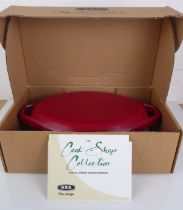 An original and unused cast iron Aga oval casserole with lid - from The Cook Shop Collection, in red