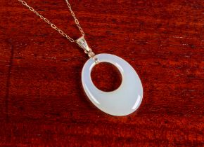 A 9ct yellow gold and pale celadon jade pendant necklace - the pierced oval jade pendant, 3.9cm.