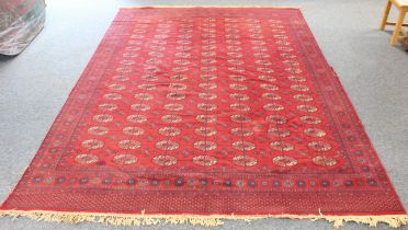 A machine-made Turkmen design carpet; red ground with seven rows of Turkmen crests (340 x 249