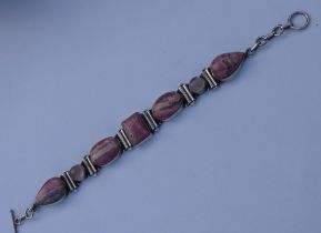 A silver bracelet mounted with mottled pink hardstones polished en cabochon, together with two small