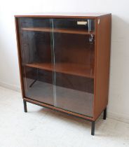 A mid 20th century teak bookcase/display case with two glass sliding doors, raised on square section