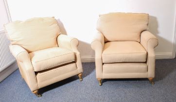 A pair of modern cream upholstered armchairs: natural bun-style turned front legs with brass castors
