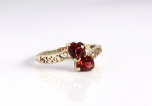 A 9ct yellow gold and garnet cross over ring - Birmingham hallmarks, the two heart shaped garnets in