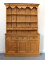 A Victorian-style pine dresser - the flared cornice with shaped apron over a closed plate- rack with