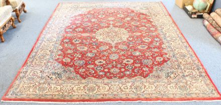 A Persian Sarouk carpet; soft red ground with ivory central medallion surrounded by palmettes with