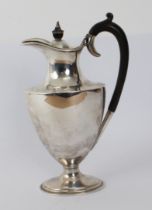 A hallmarked silver water jug in High Neoclassical style: high arched carved ebony handle above a