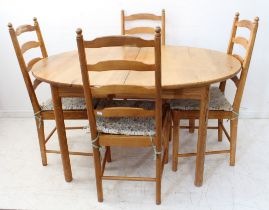 An oval-topped extending pine dining table on turned legs, together with a set of four ladderback