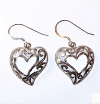 A pair of silver earrings modelled as pierced heart forms.