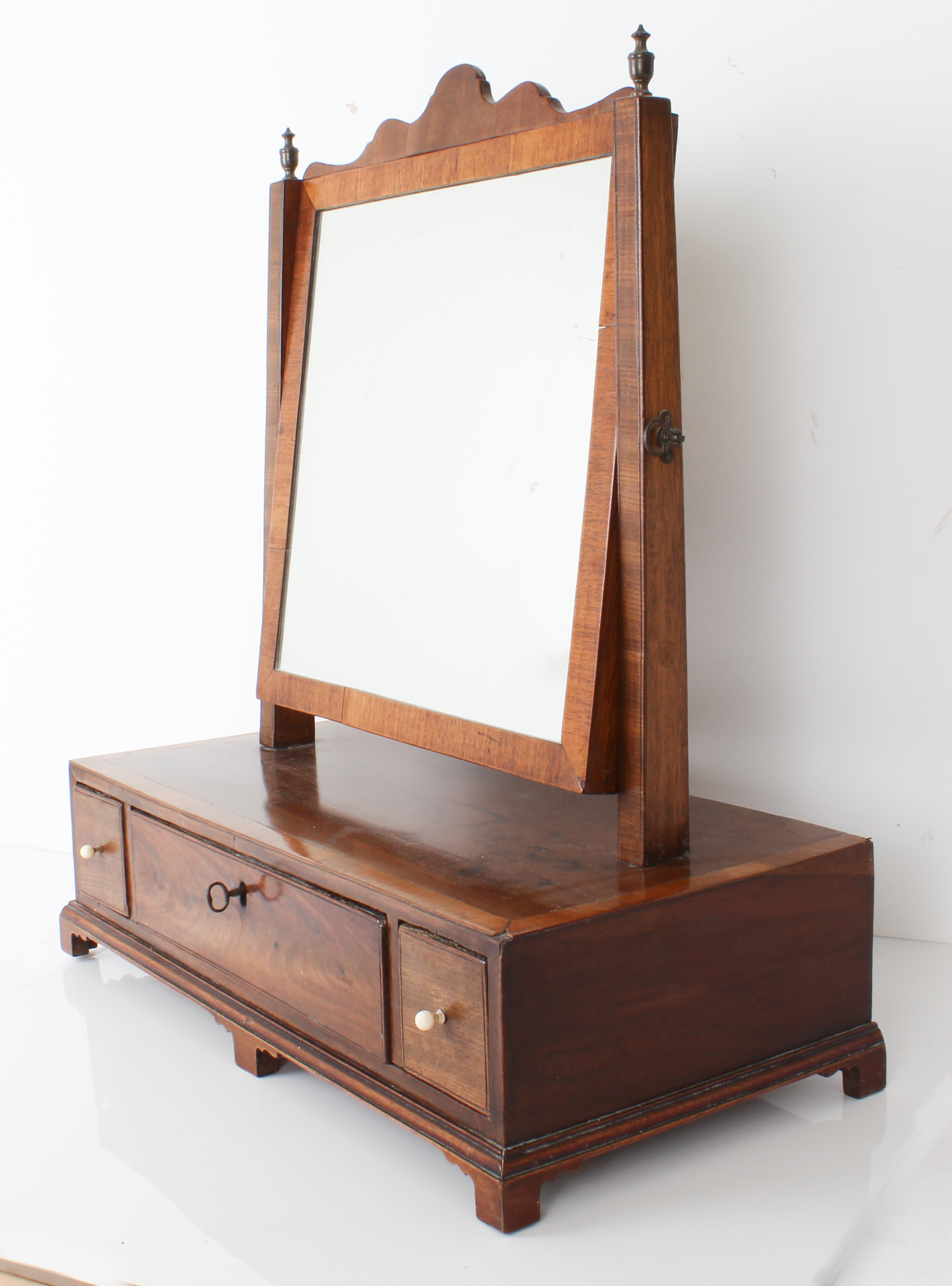 A George II period mahogany swing mirror: shaped top above the plate flanked by square taping