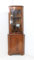 A bow-fronted mahogany freestanding corner cupboard in George III style: dentil cornice above a