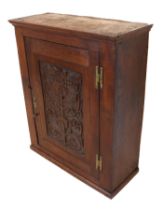 A George III joined and carved oak wall cabinet - the single panelled door carved with a flowering