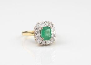 An 18ct yellow and white gold, emerald and diamond cluster ring - the central emerald, approx. 0.