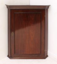 A George III style mahogany corner cupboard - early 20th century, the flared cornice over a panelled